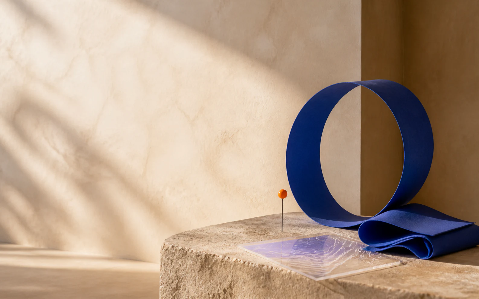 A cobalt sculptural loop and orange marker in a warm editorial setting.